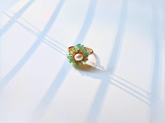 Gold ring with green gemstones on a light blue background