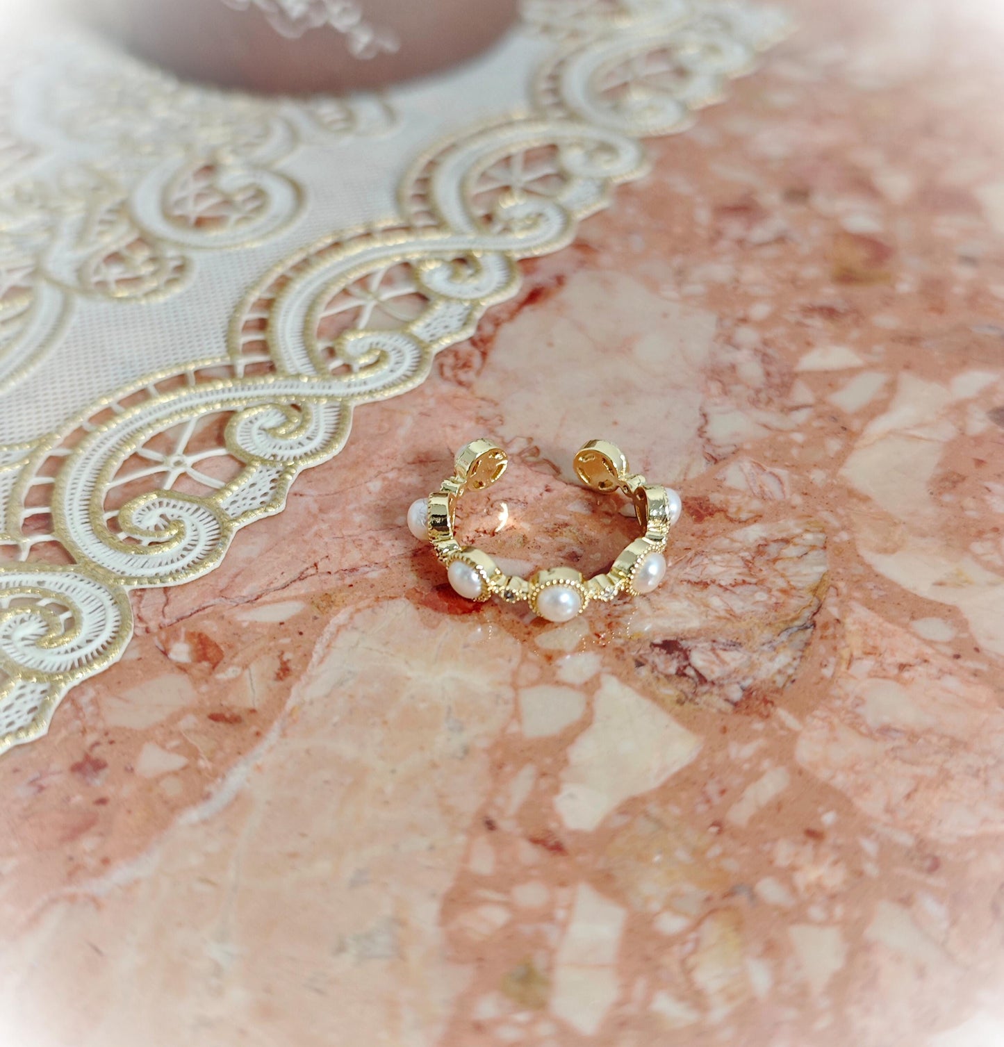 Gold hoop earring with pearls on a marble surface