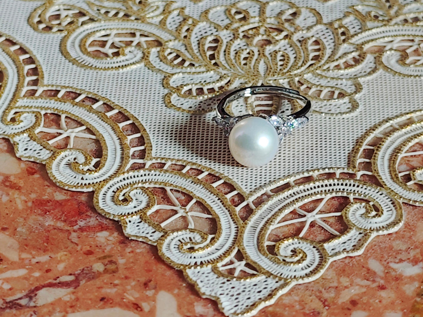 Pearl ring on a decorative lace fabric with gold embroidery