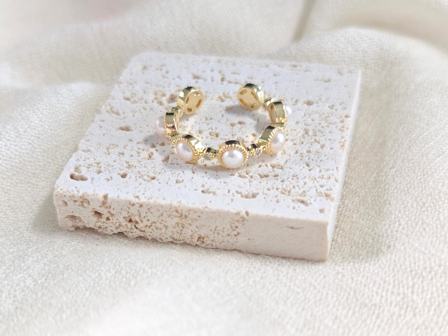 Gold hoop earring with pearls on a textured stone surface