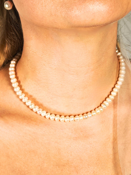 Pearl necklace worn by a person with a blurred background