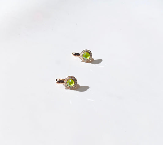 Two gold rings with green gemstones on a white background