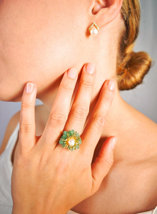 Close-up of a hand wearing a green ring with a blurred background