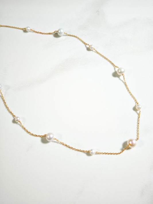 Pearl necklace with gold chain on a white background