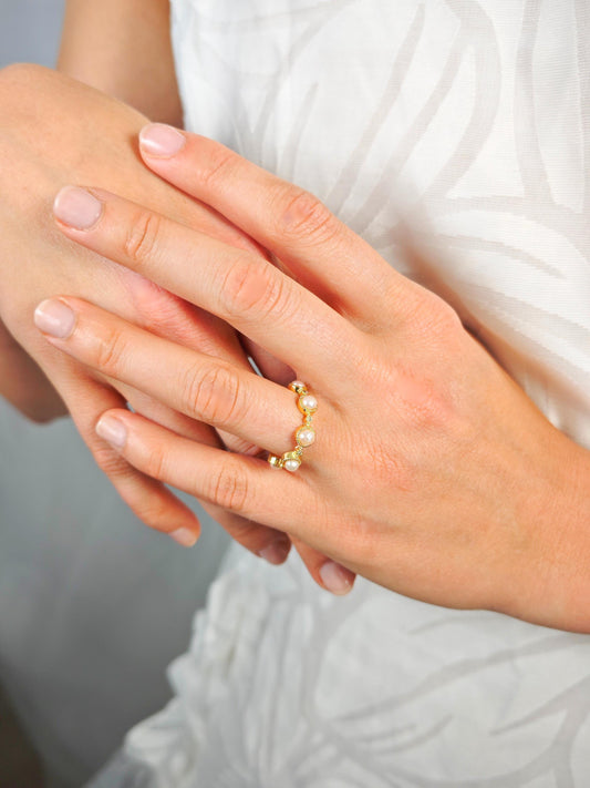 Close-up of a hand wearing a pearl ring with a blurred background