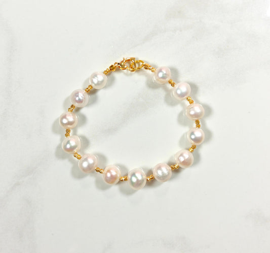 Pearl bracelet with gold clasp on a white background