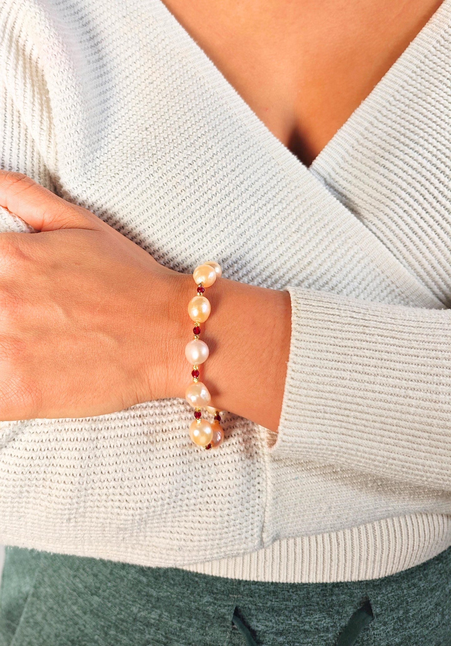 Pearl bracelet on a wrist with a light gray sweater