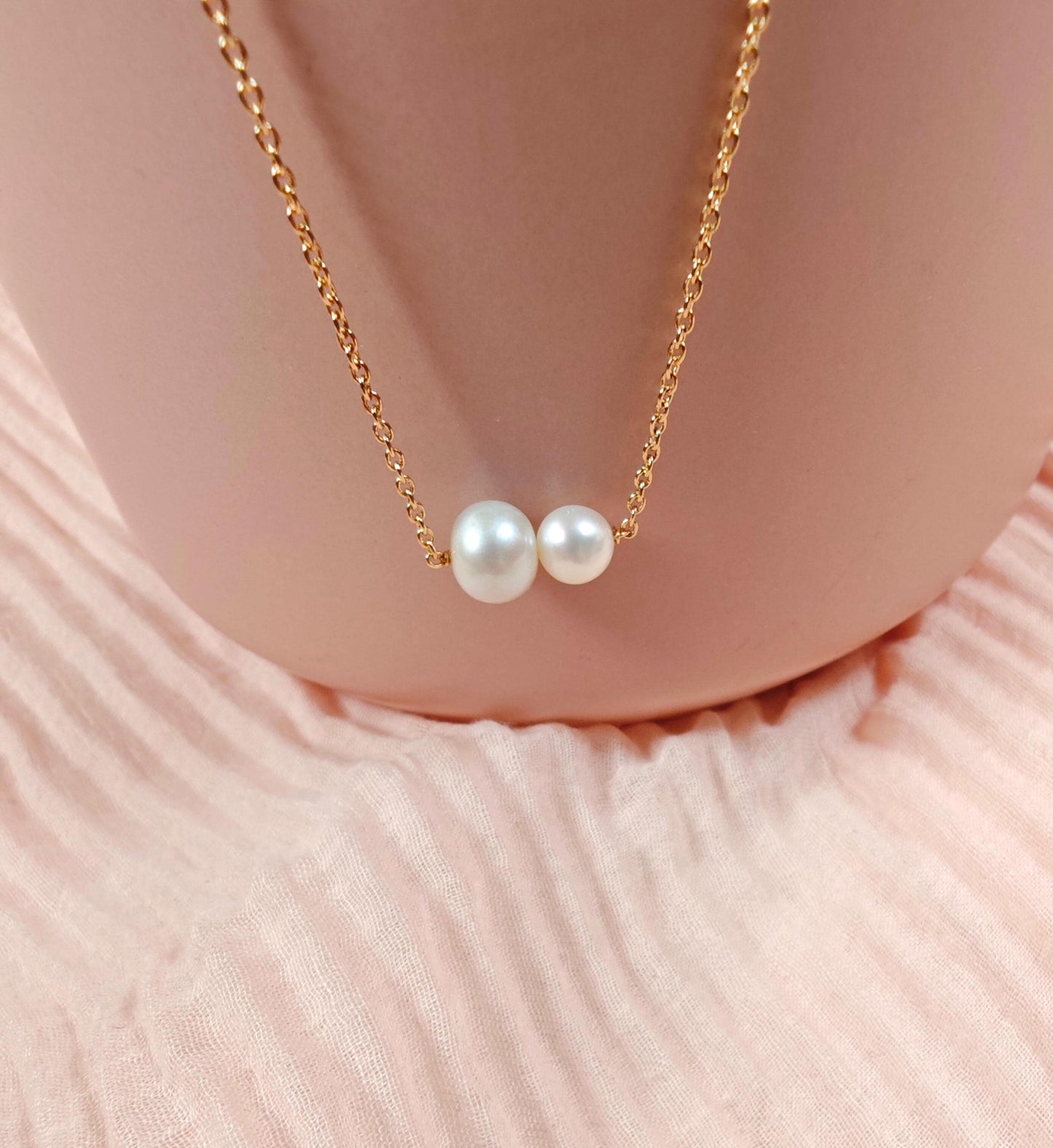 Pearl necklace with gold chain on a soft pink fabric background