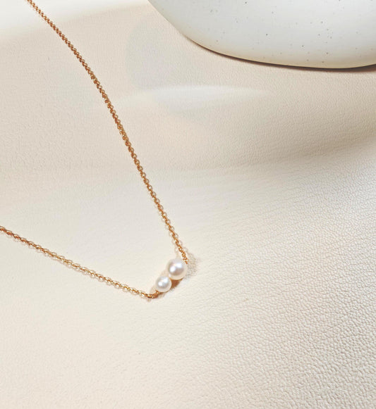 Delicate pearl necklace on a light beige surface