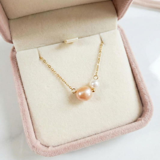 Pearl necklace on a pink jewelry box with a white background