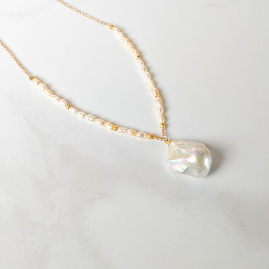 Pearl necklace with a gold chain on a light gray background