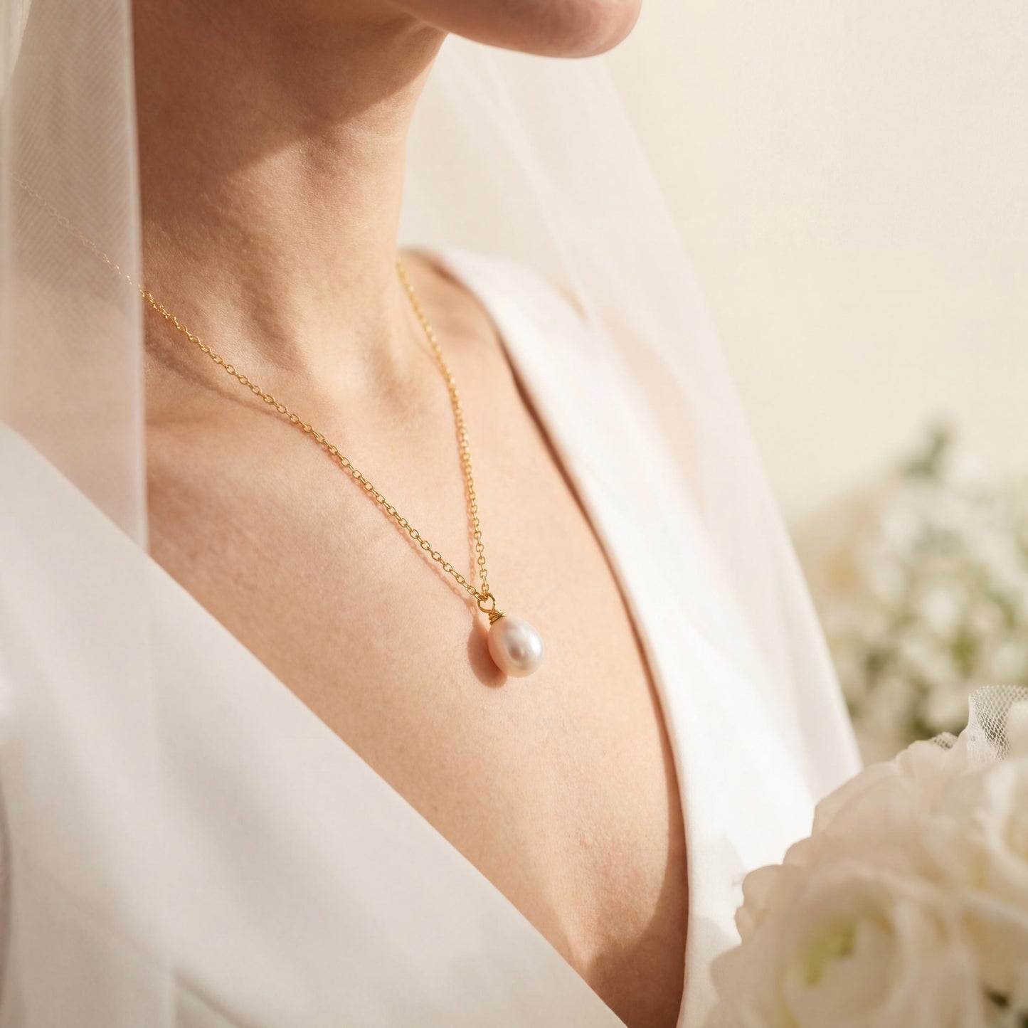 Pearl necklace worn by a person in a white outfit with a blurred floral background