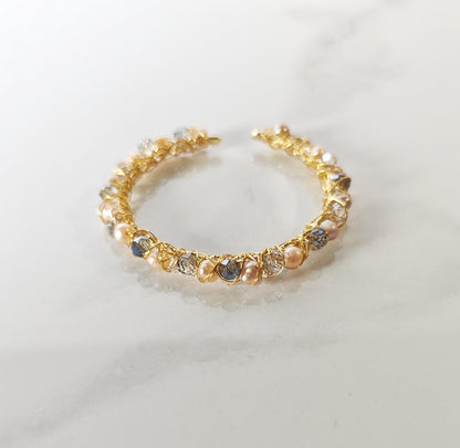 Gold bracelet with embedded pearls and crystals on a light background