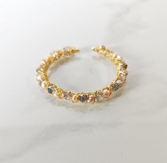Gold bracelet with embedded pearls and crystals on a light background