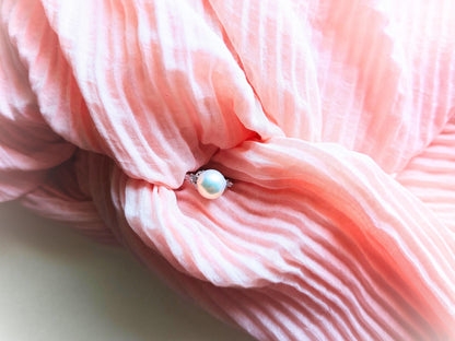 Close-up of pink yarn with a small white bead on a light background