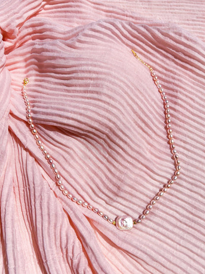 Pearl necklace on a pink textured fabric background