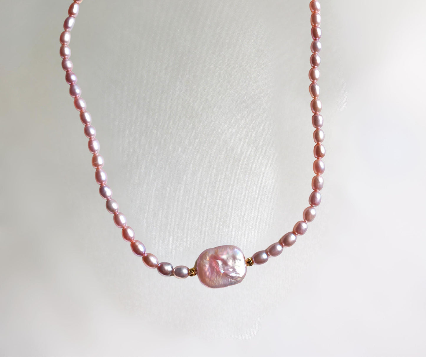Pink pearl necklace on a light gray background