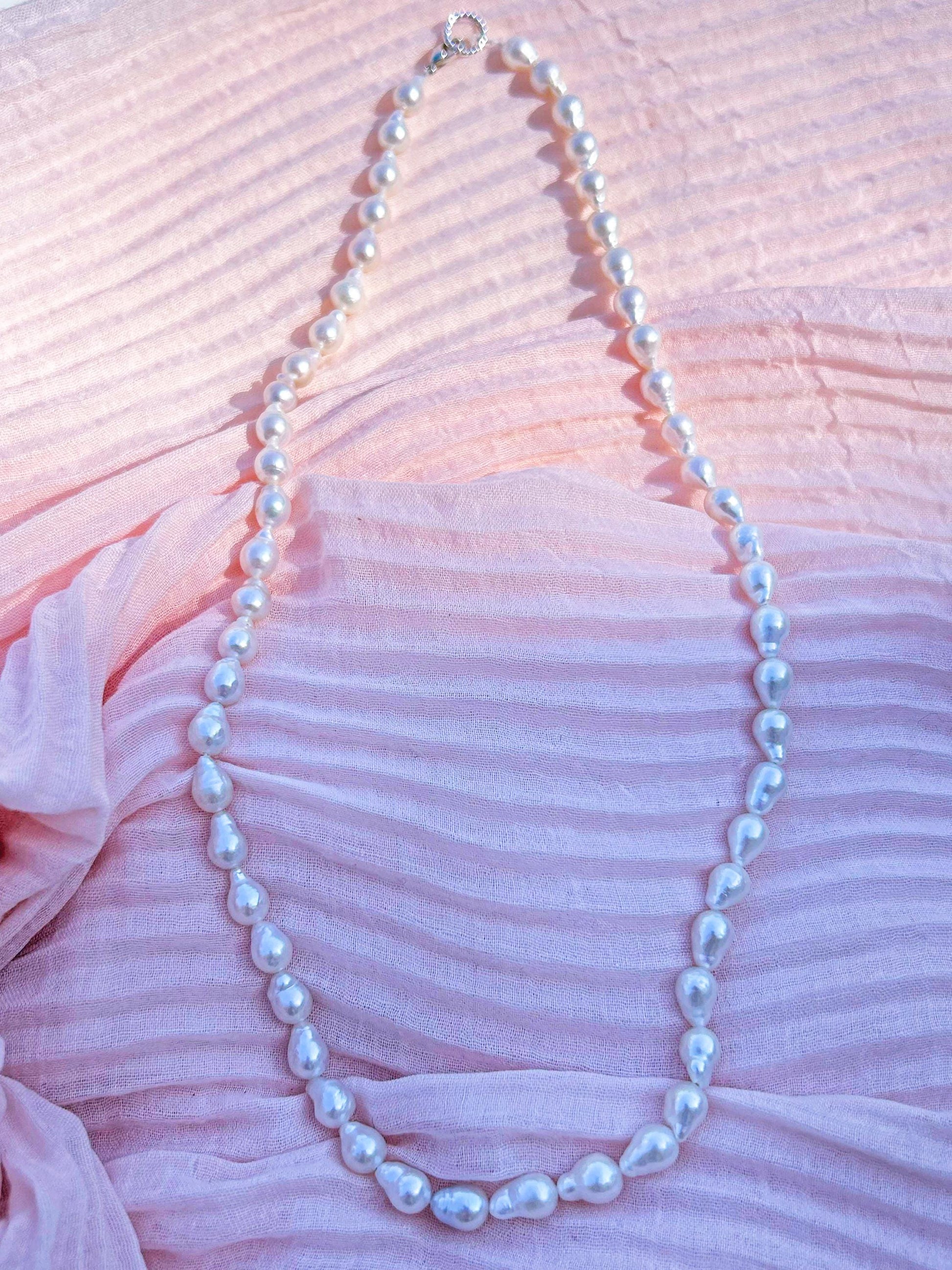 Pearl necklace on a pink textured fabric background