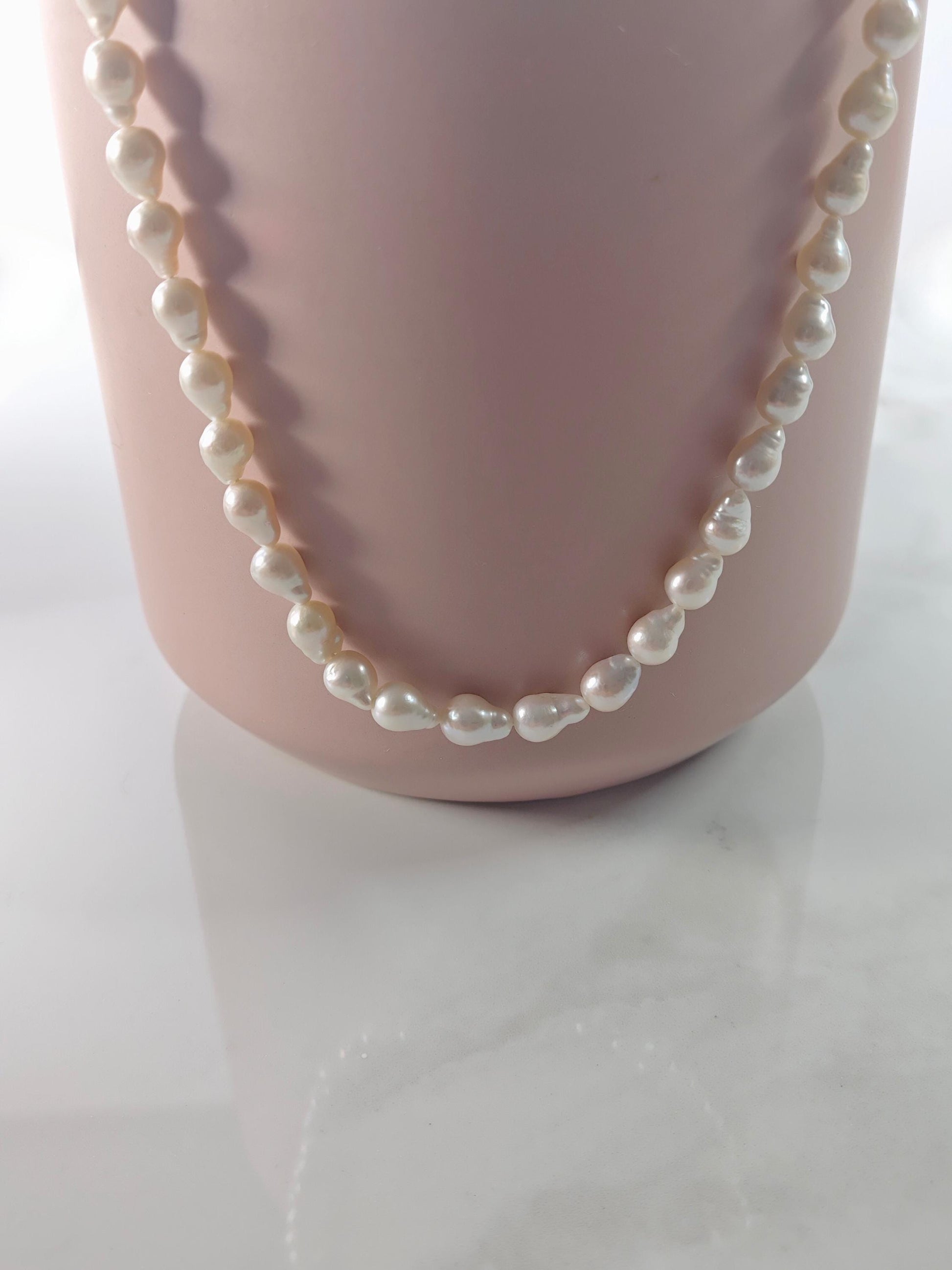 Pearl necklace on a mannequin bust against a white background