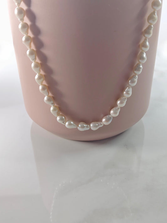 Pearl necklace on a mannequin bust against a white background