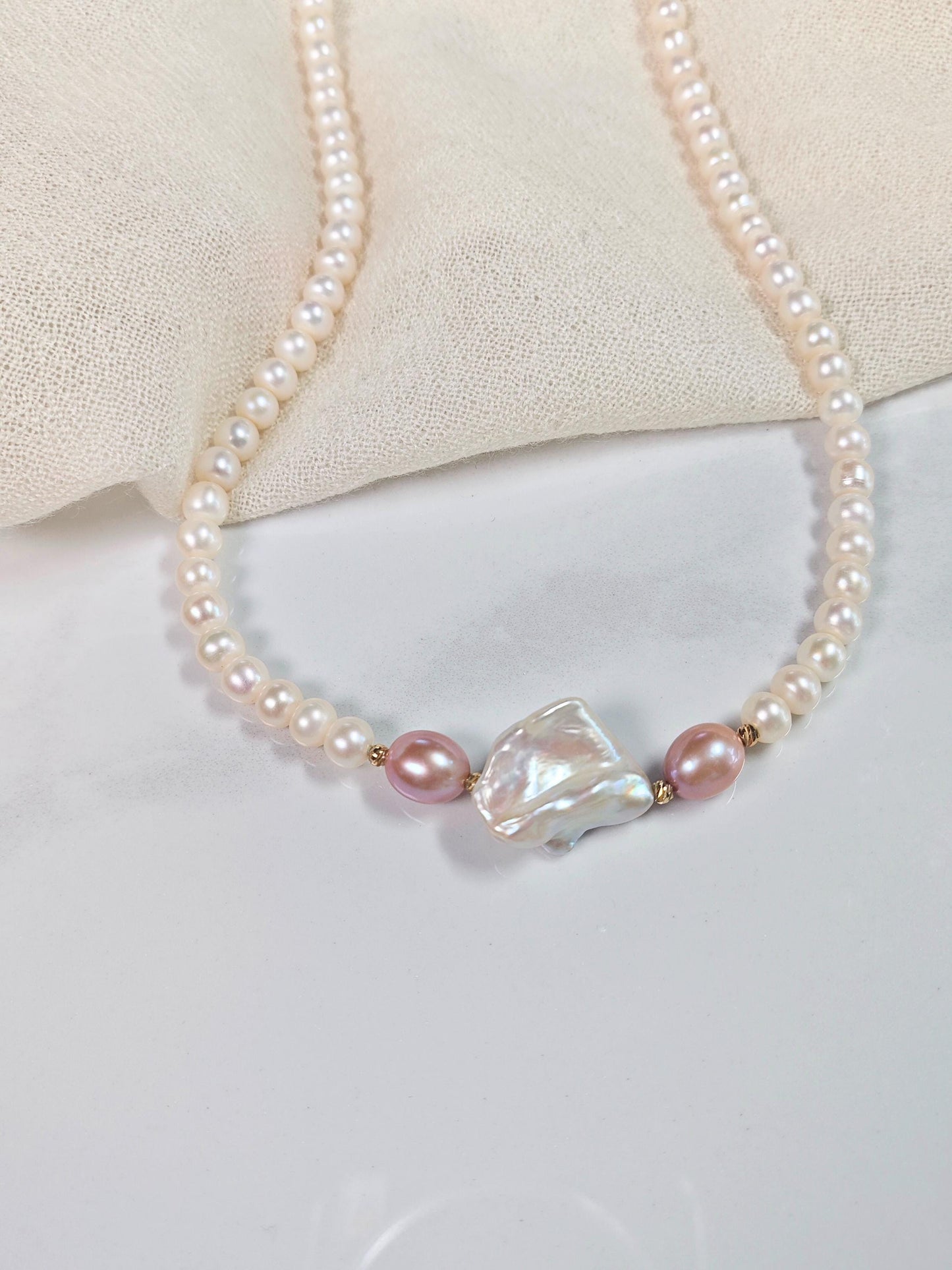 Pearl necklace with a large crystal bead on a light background