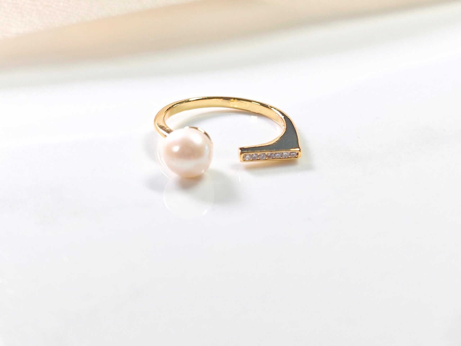 Gold ring with a pearl on a light background