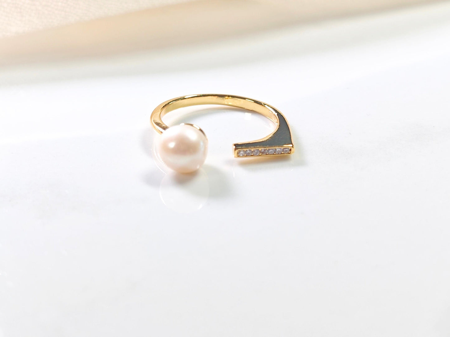 Gold ring with a pearl on a light gray background