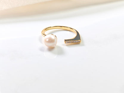 Gold ring with a pearl on a light gray background