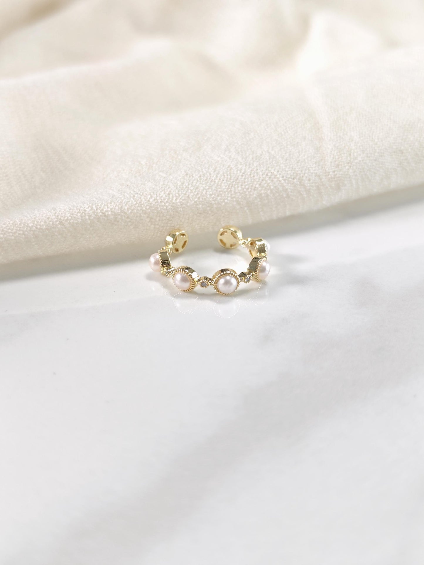 Gold ring with pearls on a white fabric background