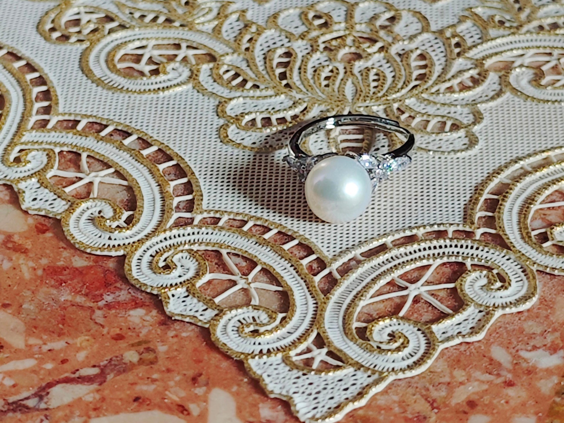 Pearl ring on a decorative lace fabric with gold embroidery