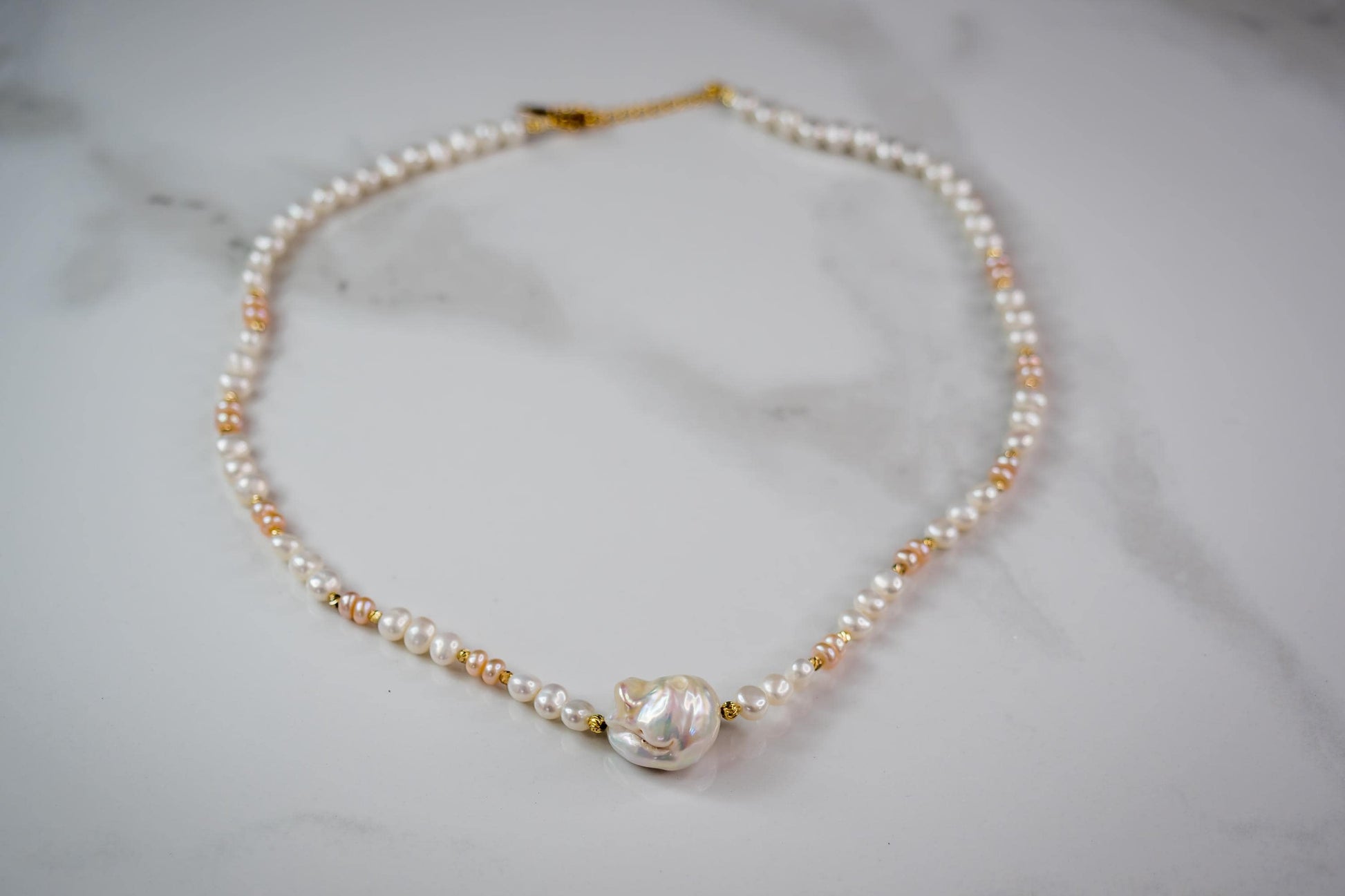 Pearl necklace with gold clasp on a marble surface