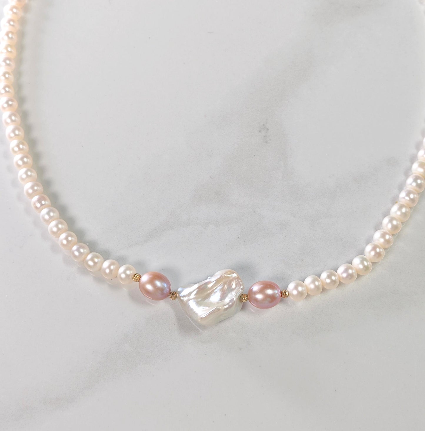 Pearl necklace with a heart-shaped pearl on a light gray background