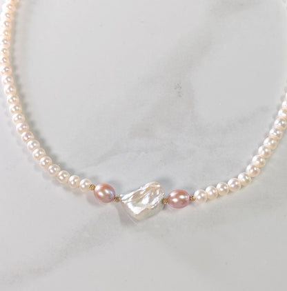 Pearl necklace with a heart-shaped pearl on a light gray background