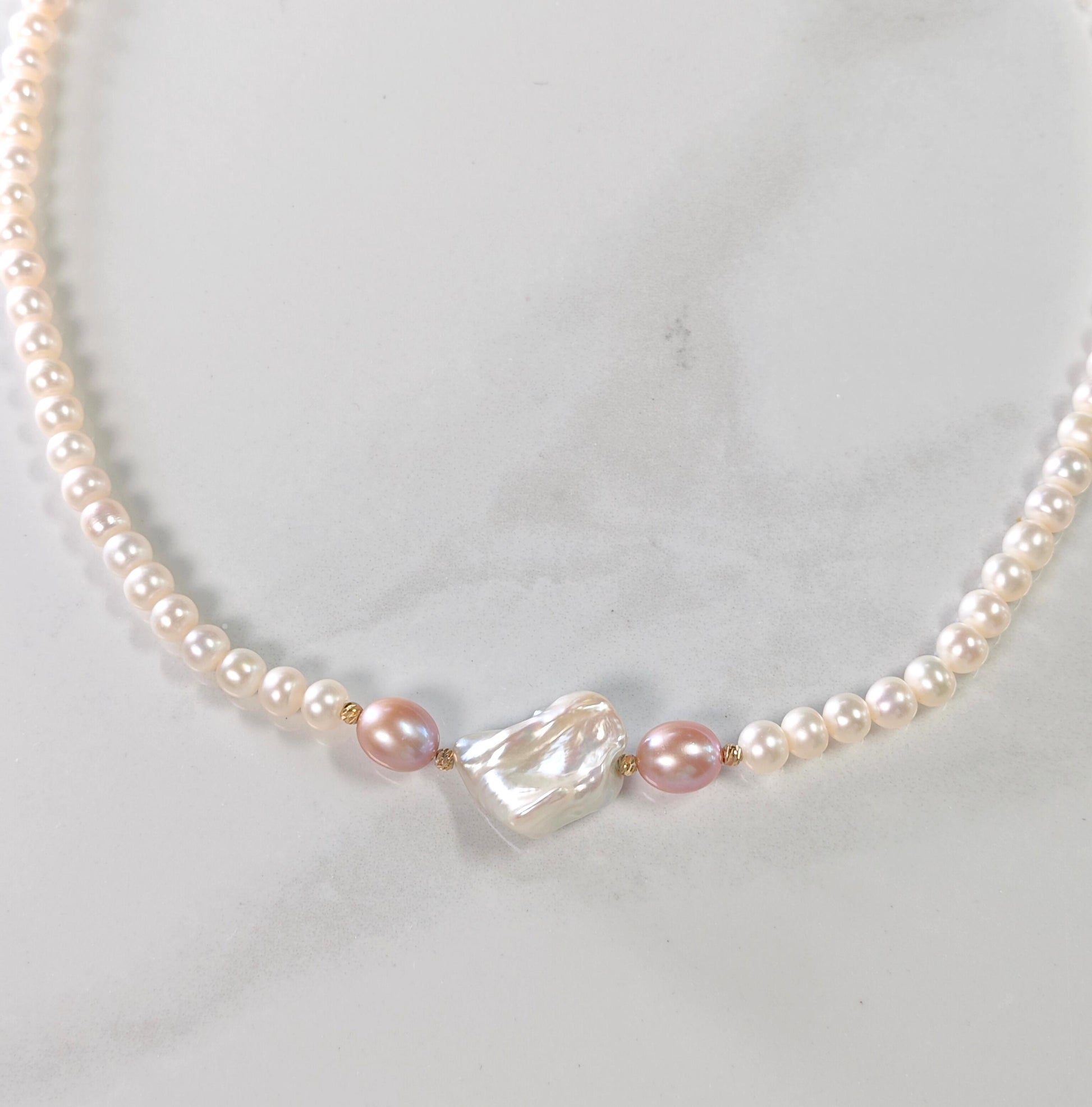 Pearl necklace with a heart-shaped pearl on a light gray background