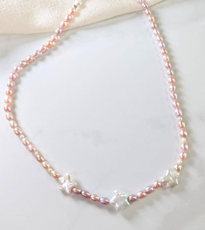 Pearl necklace with star-shaped pendants on a light background