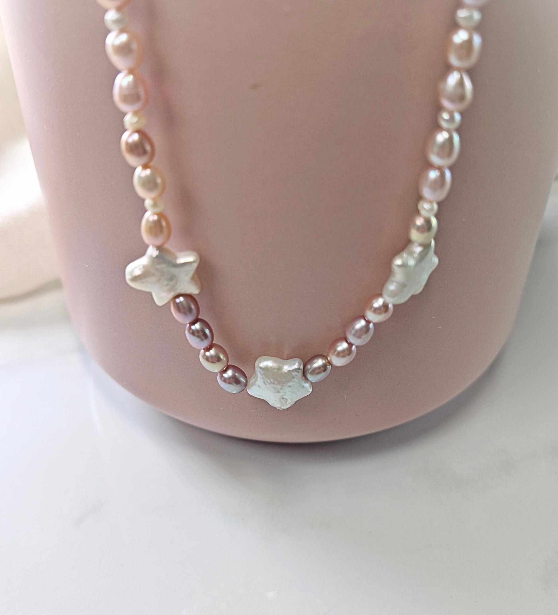 Pearl necklace with star-shaped charms on a mannequin bust.
