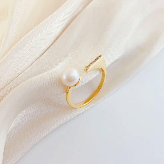 Gold ring with a pearl on a soft beige fabric background