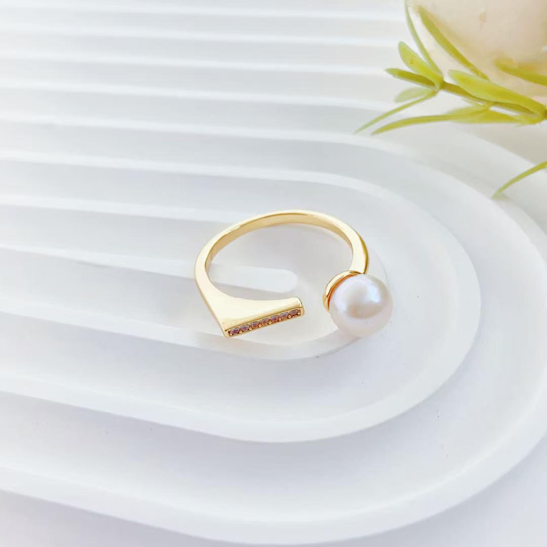 Gold ring with a pearl on a white surface