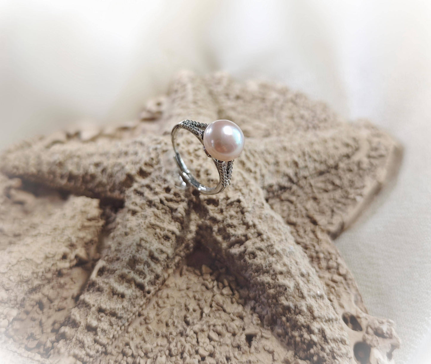 Pearl ring on a textured surface with a blurred background