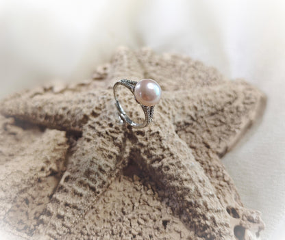 Pearl ring on a textured surface with a blurred background