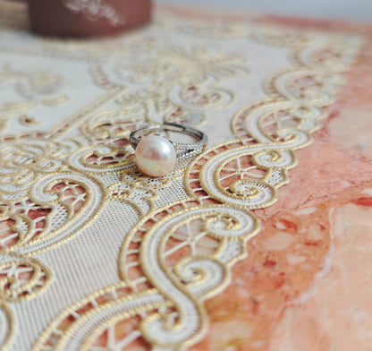 Ring with a pink pearl on a decorative lace tablecloth