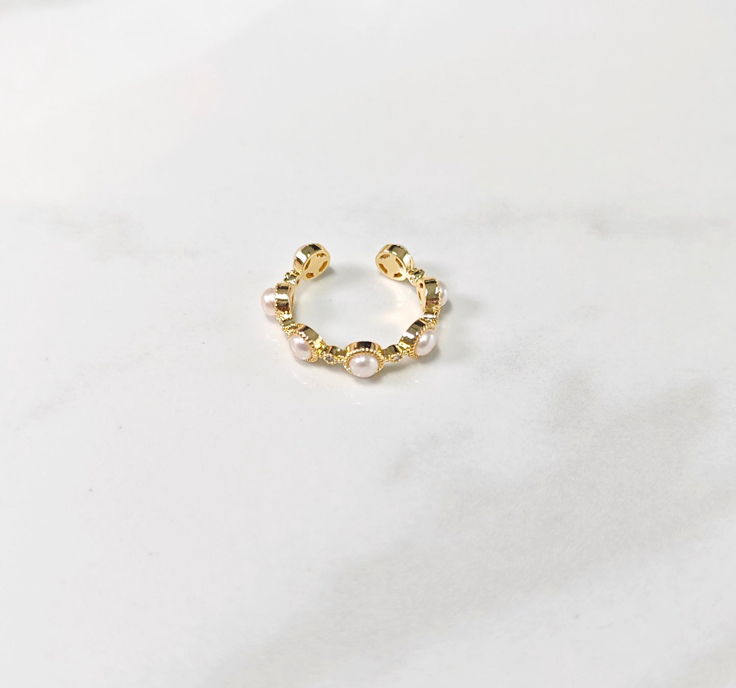 Gold hoop earring with pearls on a light gray background