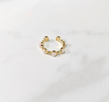 Gold hoop earring with pearls on a light gray background