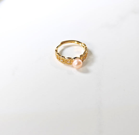 Gold ring with a pink pearl on a white background