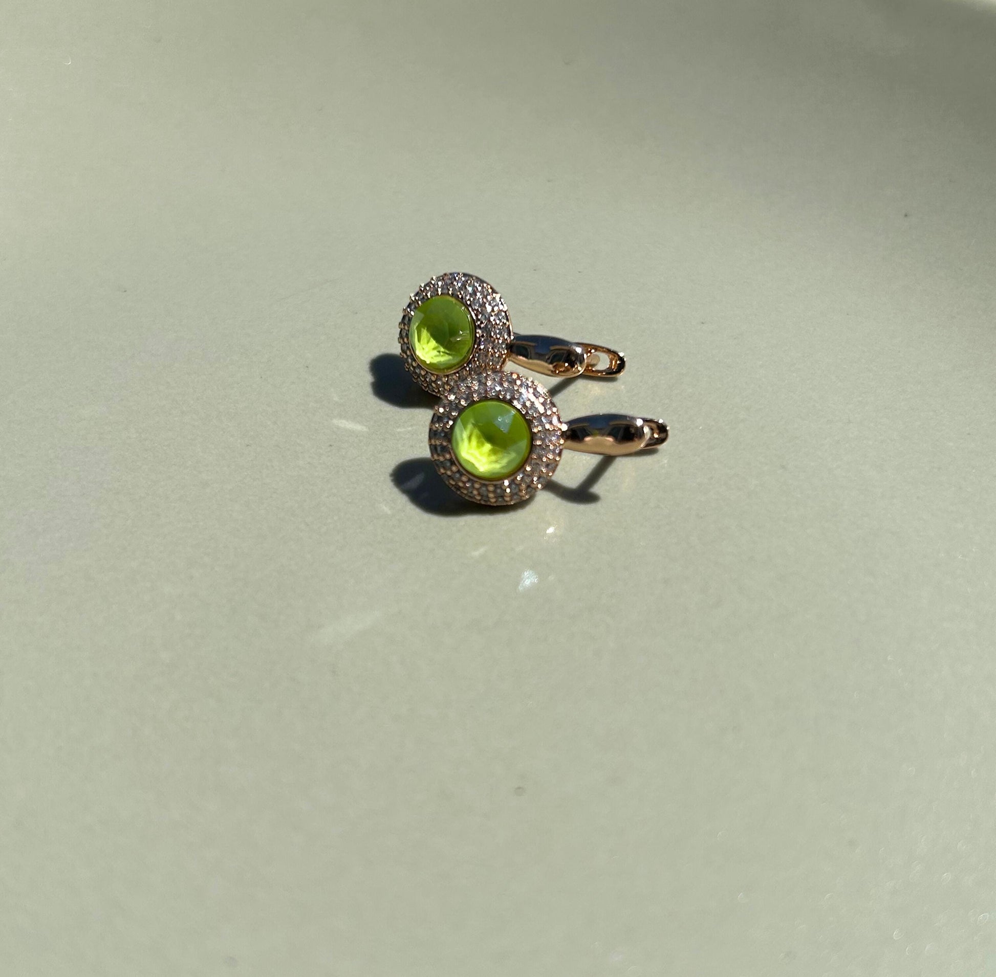 Gold ring with green gemstones on a light gray background