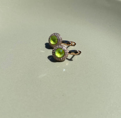 Gold ring with green gemstones on a light gray background