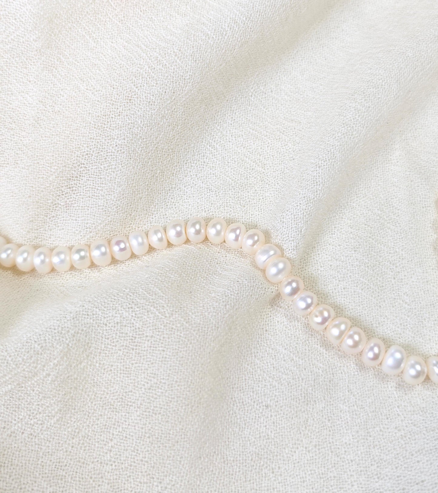 Pearl necklace on a soft white fabric background