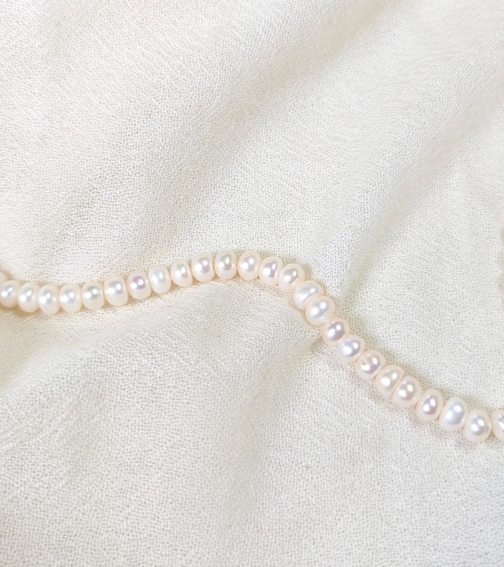 Pearl necklace on a soft white fabric background