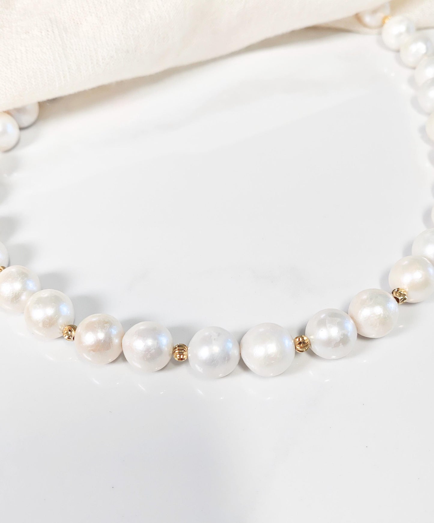 Pearl necklace with gold accents on a white background