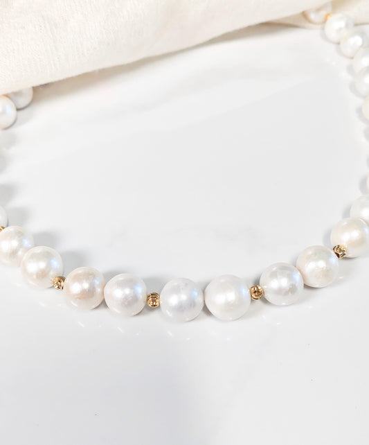 Pearl necklace with gold accents on a white background